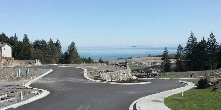 Newly paved subdivision road with curbs overlooking the ocean on Vancouver Island