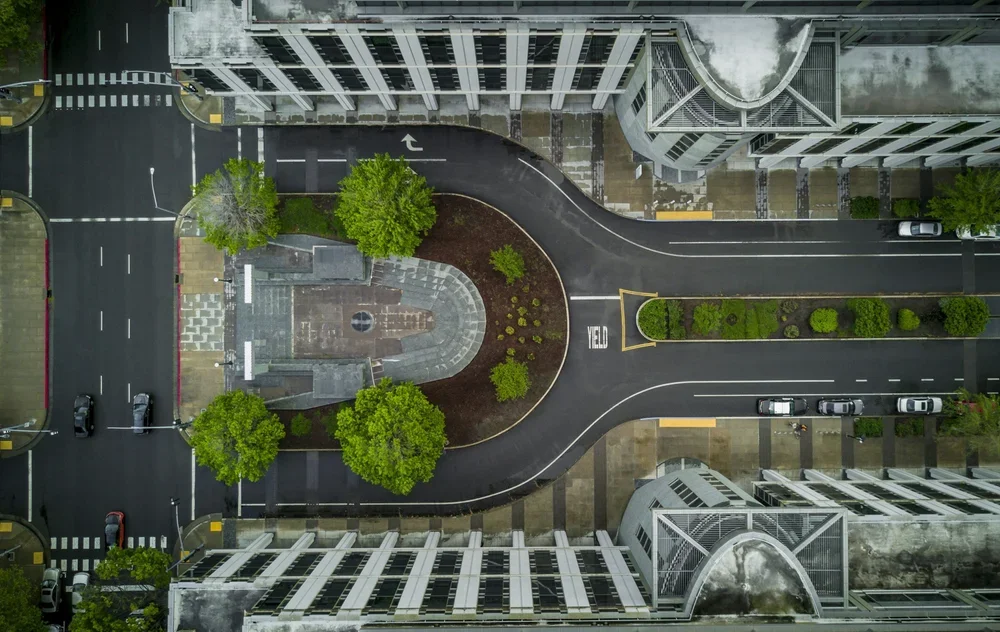 Aerial view of a landscaped roundabout and roadway beside a modern building